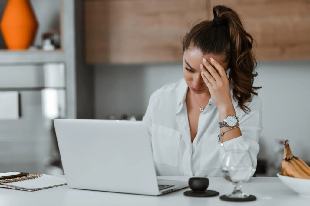 Exhausted professional woman sitting at desk with eyes closed showing signs of burnout